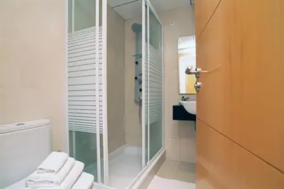 a bathroom with a shower and a toilet and a sink at Apartamentos Sitges in Sitges