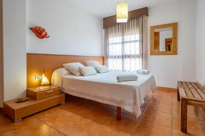 a bedroom with a bed and a table and a window at HomeHolidaysRentals Adara in Pineda de Mar
