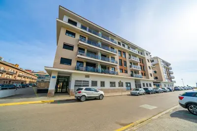 a large building with cars parked in a parking lot at HomeHolidaysRentals Adara in Pineda de Mar