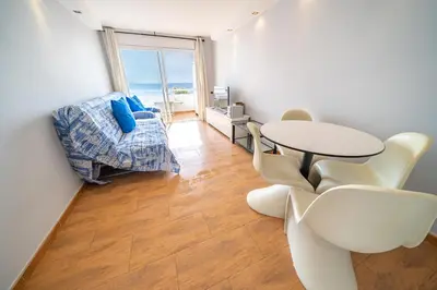 a living room with a table and chairs and a window at HomeHolidaysRentals Marella - Costa Barcelona in Pineda de Mar