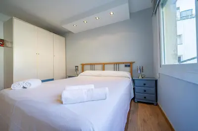 a bedroom with a large white bed and a window at HomeHolidaysRentals Marella - Costa Barcelona in Pineda de Mar