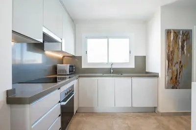 a kitchen with white cabinets and a sink and a window at Sitges Spaces Oasis Penthouse 3 Bedroom, 2 Bathroom, Terrace, Pool, Sleeps up to 6 in Sitges