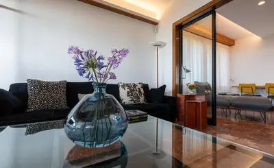 a vase with flowers on a glass table in a living room at Villa Can Bagués in Mataró
