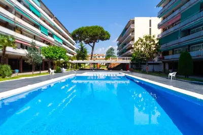 a large blue swimming pool next to a building at Apartment Llavaneres I in Sant Andreu de Llavaneres