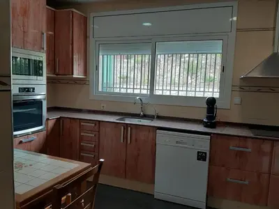 a kitchen with wooden cabinets and a sink and a window at Habitaciones en Villa Coliving Casa Rural in San Fausto de Campcentellas