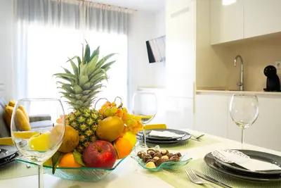 a bowl of fruit on a table with wine glasses at Castell Beach Aparthotel in Castelldefels