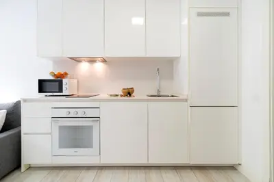 a kitchen with white cabinets and a microwave at Castell Beach Aparthotel in Castelldefels