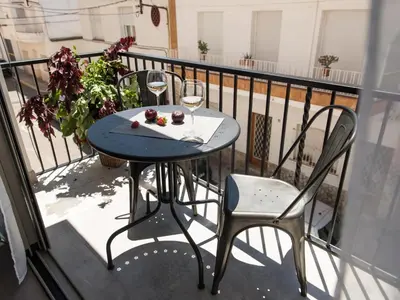 a table and chairs on a balcony with a glass of wine at Sitges Spaces Seaside Beach Flat- 4 Bedroom, 2 Bathroom, Terrace, Near Beach in Sitges