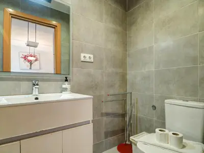 a bathroom with a toilet and a sink and a mirror at Linda Vista Oasis Penthouse by Hello Homes Sitges in Sitges