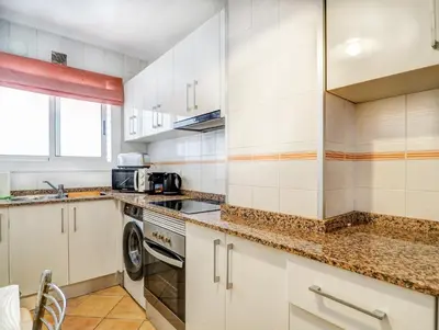 a kitchen with white cabinets and a washer and dryer at Linda Vista Oasis Penthouse by Hello Homes Sitges in Sitges