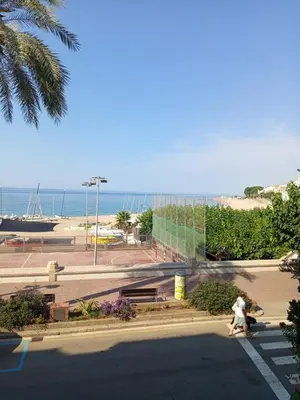 two people walking down a street near the beach at Beachfront Apartment with Sea Views & Private Parking in San Pol de Mar