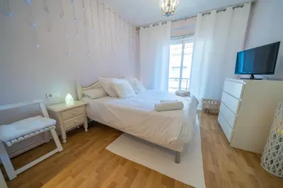 a white bedroom with a bed and a tv at HomeHolidaysRentals Plume - Costa Barcelona in Pineda de Mar