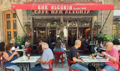 a group of people sitting at tables in front of a restaurant at Mercat Sant Antoni 4 in Barcelona