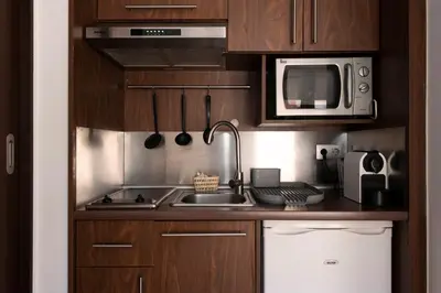 a kitchen with wooden cabinets and a sink and a microwave at Aparthotel Centric in Castelldefels
