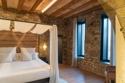 a bedroom with a large bed in a stone wall at Les Quingles in Calders