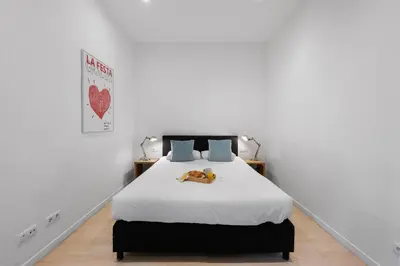 a white bedroom with a bed with a dog on it at AB Gran de Gràcia in Barcelona