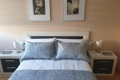 a bedroom with a bed with two night stands and two lamps at Apartamento para 5 personas frente al mar con piscina y parking in Cubelles
