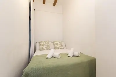a bed with white pillows and a green blanket at Stay Unique Apartments Corsega in Barcelona