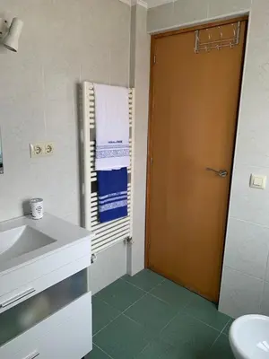 a bathroom with a sink and a wooden door at CASA la PAU in Vilassar de Mar