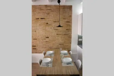 a dining room with a wooden table and a brick wall at Barcelona Industrial Style Apartment in Hospitalet de Llobregat