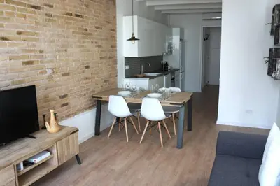 a living room with a dining room table with white chairs at Barcelona Industrial Style Apartment in Hospitalet de Llobregat