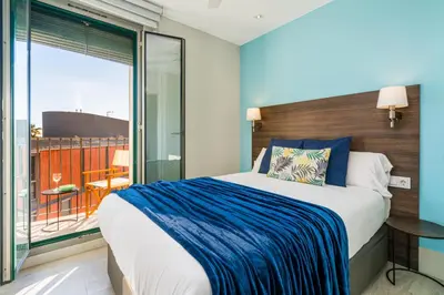a bedroom with a large bed and a balcony at Kronos on the beach Suite 4 in Barcelona
