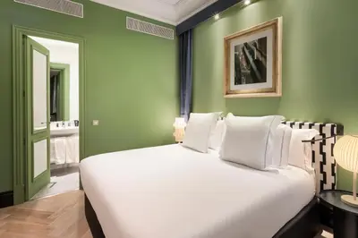 a bedroom with a large white bed with green walls at One Shot Aragó in Barcelona