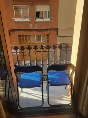 two blue chairs on a balcony with a building at Apartamento Cerca del Mar in Badalona