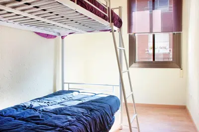 a bunk bed in a room with a ladder at Apartamento Cerca del Mar in Badalona