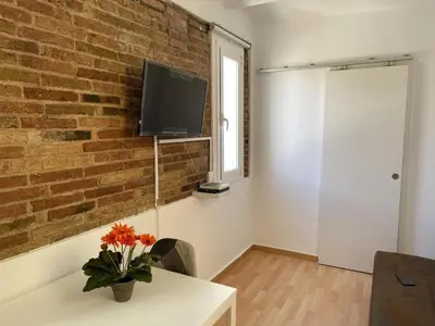 a living room with a brick wall and a tv at Ático ideal en Barcelona in Barcelona