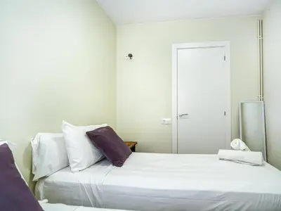 a bedroom with two beds with white sheets and purple pillows at Beach Matucana Apartment by Hello Homes Sitges in Sitges