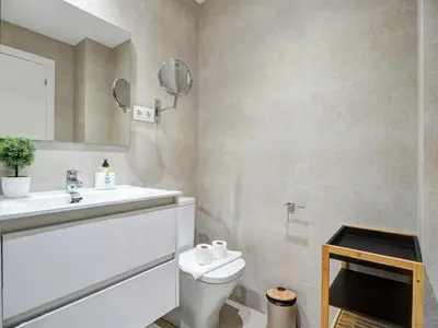 a bathroom with a toilet and a sink and a mirror at Beach Matucana Apartment by Hello Homes Sitges in Sitges