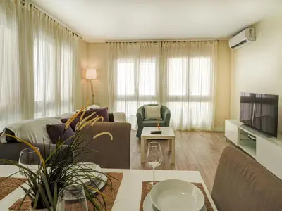 a living room with a couch and a tv and a table at Beach Matucana Apartment by Hello Homes Sitges in Sitges