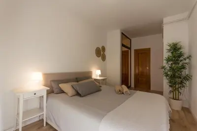 a white bedroom with a white bed and a plant at INNOUTHOME Apartamento Eixample Barcelona in Barcelona