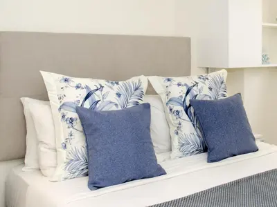 a white bed with blue and white pillows on it at Sitges Spaces Oasis Suites- 4 Bedroom, 4 Ensuite Bathrooms, Terrace, Pool, Sitges Centre in Sitges