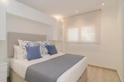 a white bedroom with a large bed with blue pillows at Sitges Spaces Oasis Suites- 4 Bedroom, 4 Ensuite Bathrooms, Terrace, Pool, Sitges Centre in Sitges