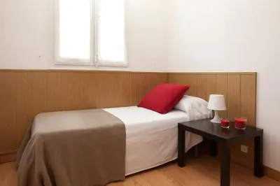 a bedroom with a bed with a red pillow and a table at Click&Flat Floridablanca in Barcelona