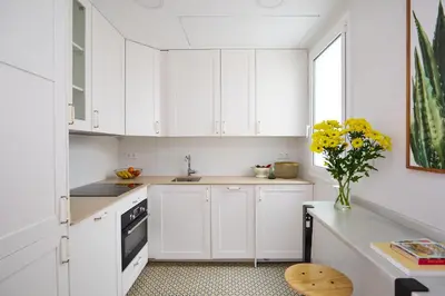 a kitchen with white cabinets and a vase of yellow flowers at Casa Cosi - El Farro 3 in Barcelona