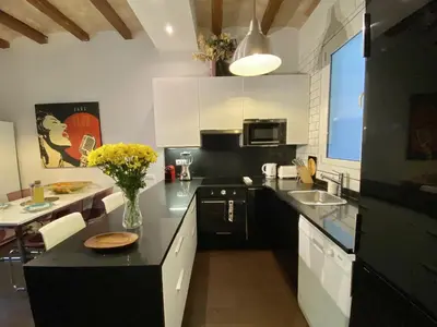 a kitchen with white cabinets and a black counter top at Sant antoni apartment in Barcelona
