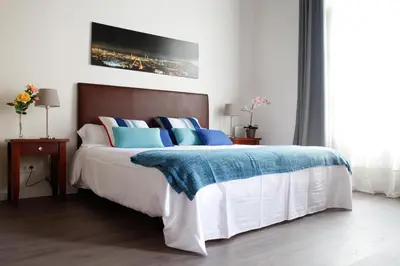 a bedroom with a large bed with blue pillows at Colom Apartments in Barcelona