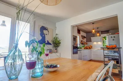 a kitchen with a wooden table with two glasses of wine at Villa Elysian by Hello Homes Sitges in Sant Pere de Ribes