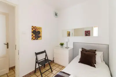 a white bedroom with a bed and a chair at rentBCN City Center Apartment in Barcelona