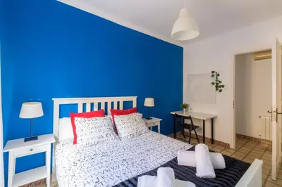 a blue bedroom with a white bed with red pillows at rentBCN City Center Apartment in Barcelona