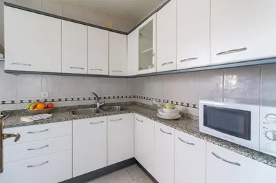 a white kitchen with white cabinets and a microwave at rentBCN City Center Apartment in Barcelona