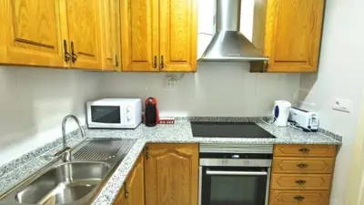 a kitchen with wooden cabinets and a sink and a microwave at Homenfun Barcelona Paralelo in Barcelona