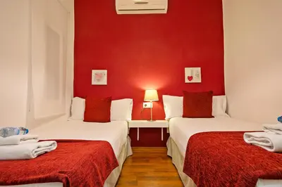 two beds in a room with a red wall at Alcam Enamorats in Barcelona