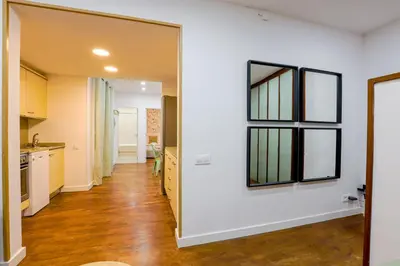 a kitchen with white walls and wooden floors and a mirror at Alcam Torrent in Barcelona