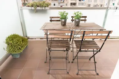 a wooden table and chairs on a balcony with potted plants at Alcam Aribau in Barcelona