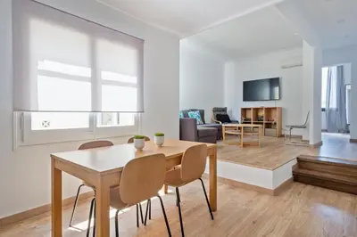 a dining room and living room with a table and chairs at Blau Atic Apartment in Barcelona