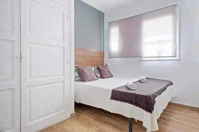 a white bedroom with a bed and a window at Blau Atic Apartment in Barcelona
